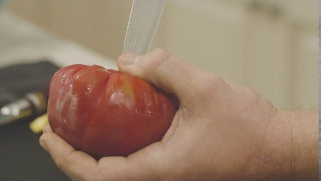 Close-up of a knife slicing a tomato