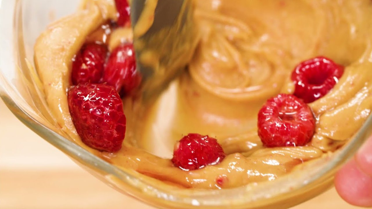 Spoon swirling raspberries into Fokken Nuts peanut butter