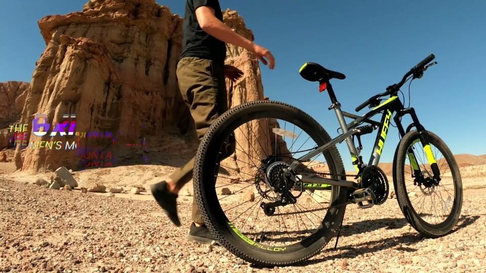 Rider walking a Huffy mountain bike through red rock desert