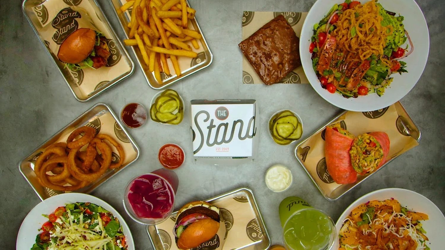Overhead spread of burgers, fries, salads and drinks from The Stand